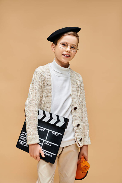 Young boy in glasses and a sweater holds a clapper. - Photo, Image