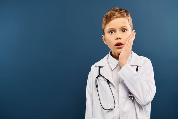 Jeune garçon en chemise blanche et stéthoscope, prétendant être médecin sur fond bleu. - Photo, image