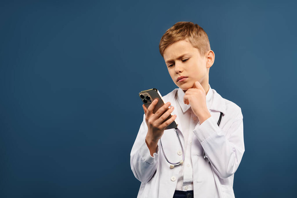 Niño en bata de laboratorio blanco cautivado por la pantalla del teléfono inteligente. - Foto, Imagen