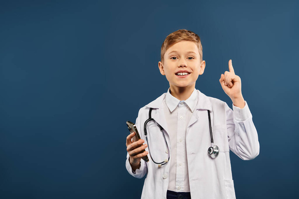 Jeune garçon dans les médecins manteau pointant avec enthousiasme. - Photo, image