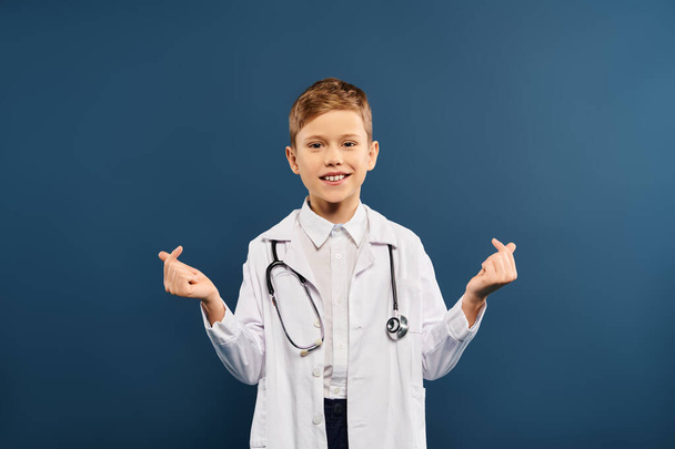 Νεαρό αγόρι σε ιατρική παλτό και στηθοσκόπιο σε μπλε φόντο. - Φωτογραφία, εικόνα