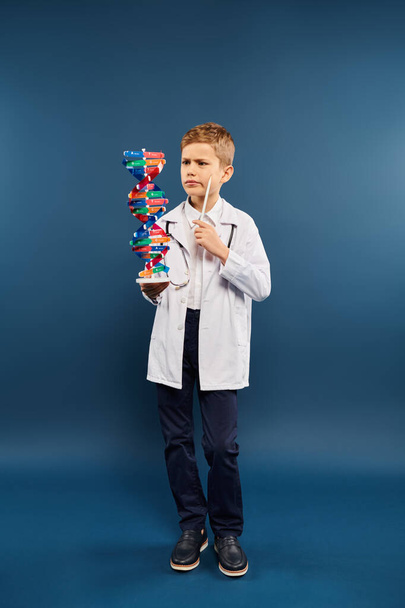 Preadolescent boy, dressed as a doctor, holds a model of a structure. - Photo, Image