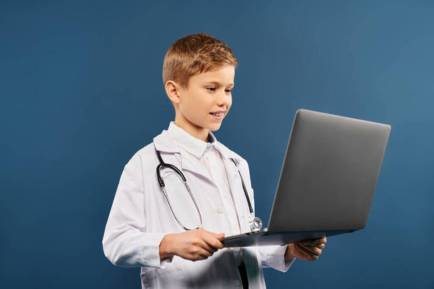 Ein kleiner Junge, als Arzt verkleidet, konzentriert sich auf seinen Laptop. - Foto, Bild
