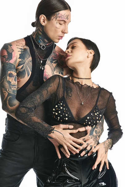 Un jeune couple élégant, orné de tatouages, posant pour une photo dans un studio sur un fond gris. - Photo, image