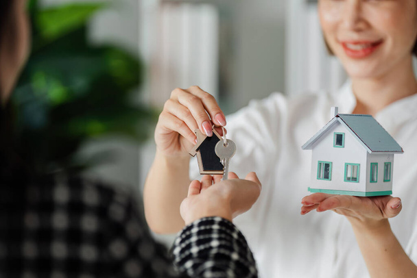 Agente imobiliário segurando chave e casa e dá-lo ao cliente após a assinatura do acordo. - Foto, Imagem