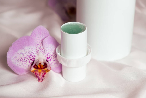 Detergente líquido natural para ropa con un aroma floral sobre un fondo de tela satinada - Foto, Imagen