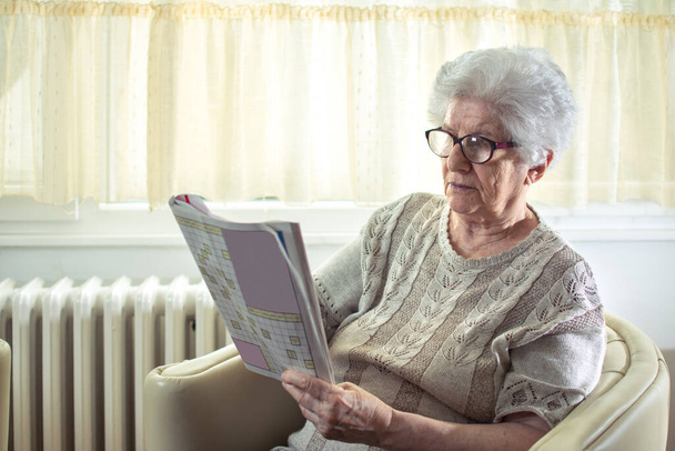Mujer mayor resolviendo un crucigrama en casa - Foto, Imagen