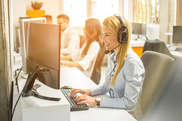 Seitenansicht der Warteschlange von Callcenter-Mitarbeitern lächeln und arbeiten am Computer - Foto, Bild