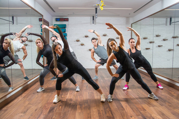 Gruppe fitter Sportler trainiert und dehnt sich im Fitnessstudio - Foto, Bild
