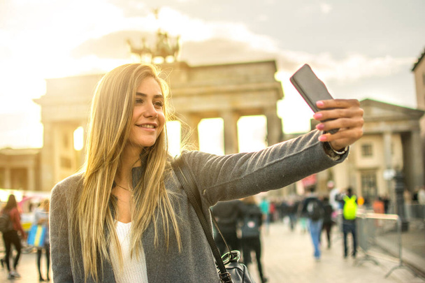 Hermosa chica rubia tomando selfie frente a la Puerta de Brandeburgo en la ciudad de Berlín, Alemania - Foto, Imagen