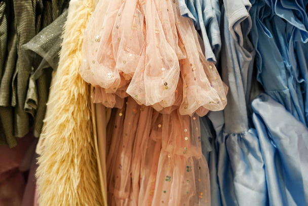 Παιδικά φορέματα κοριτσιών που κρέμονται σε κρεμάστρες στο μαγαζί - Φωτογραφία, εικόνα