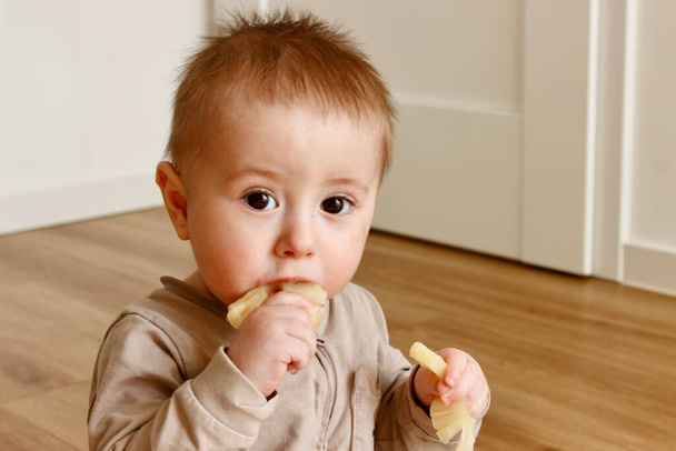 Un ragazzino assaggia un pezzo di ananas . - Foto, immagini
