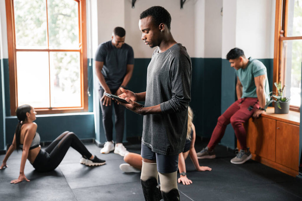 A group of people are working out in a gym, exercising their arms, legs, muscles, and thighs. They are sharing the space in the building with large windows and sturdy flooring - Photo, Image