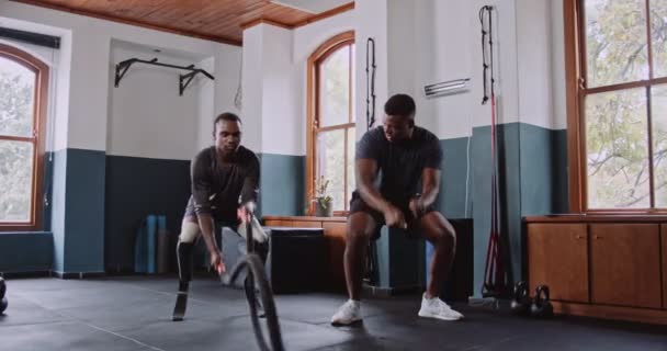 Um casal está se exercitando no ginásio, com foco na construção de força em suas pernas e coxas. Eles estão usando equipamentos como uma mesa, cadeira e planta para ajudar em seus exercícios - Filmagem, Vídeo
