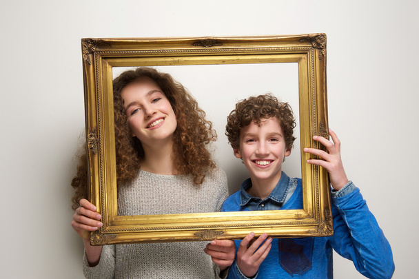 Счастливые мальчик и девочка с рамкой для фотографий
 - Фото, изображение