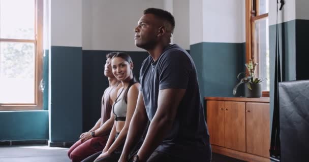 Un groupe d'individus sont assis sur le plancher de bois d'une salle de gym, participant à un événement de musculation axé sur leurs cuisses, leurs poitrines et leurs jambes humaines - Séquence, vidéo