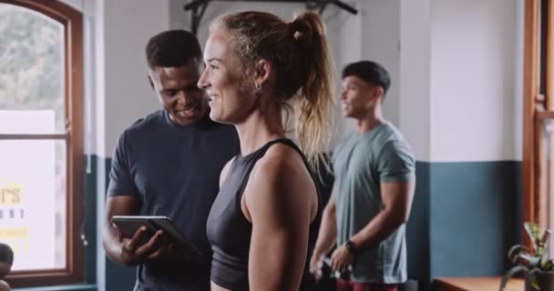  Afroamerykanin trener osobisty używając tabletu trenuje białą kobietę w studio w krytej sali gimnastycznej. Wysokiej jakości materiał 4k - Materiał filmowy, wideo
