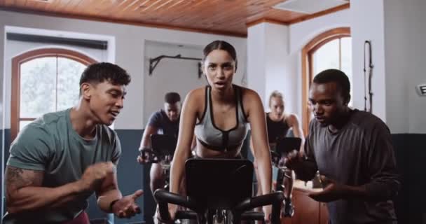 Een groep mensen fietst op hometrainers in een fitnessruimte in een gebouw. Ze delen het leuke evenement, genieten van de vrije tijd uit te werken hun dijen - Video
