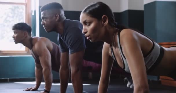 Mężczyzna i kobieta ćwiczą razem na siłowni, dzieląc chwilę wytchnienia podczas pompek, aby wzmocnić mięśnie, klatkę piersiową, brzuch i uda. - Materiał filmowy, wideo