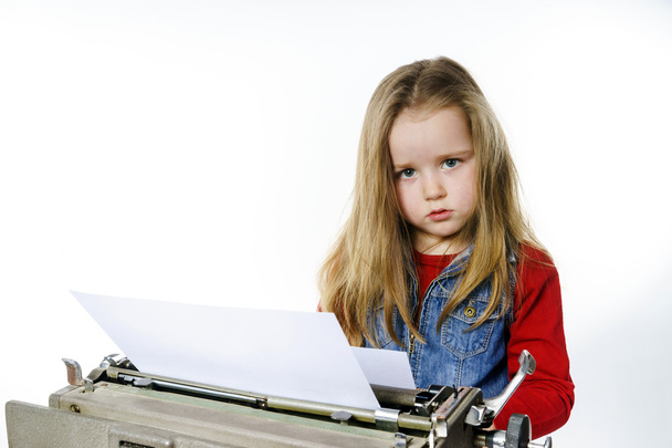 Cute little girl typing on vintage typewriter keyboard - Foto, Imagem