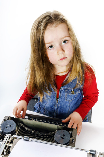 Cute little girl typing on vintage typewriter keyboard - Foto, immagini