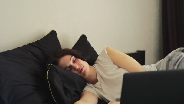 Κουρασμένη κυρία ξαπλωμένη στο κρεβάτι και κοιμάται δίπλα στο λάπτοπ της. Αργή κίνηση. Εργασία στο σπίτι, έννοια του τρόπου ζωής - Πλάνα, βίντεο