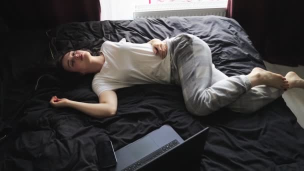 Dame slaapt op het bed, rusten na het werken online op laptop thuis. Langzame beweging. Thuis werken, lifestyle concept - Video