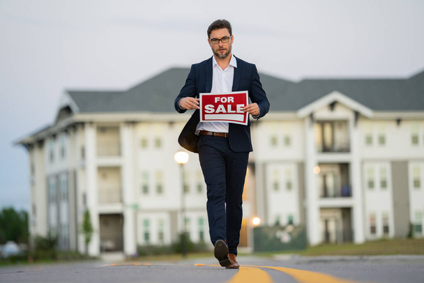 Buying and choosing housing. real estate agent in a suit holding a sign for rent or lease. Real estate agent holding pen pointing at contract document for client to sign home purchase agreement - Photo, Image