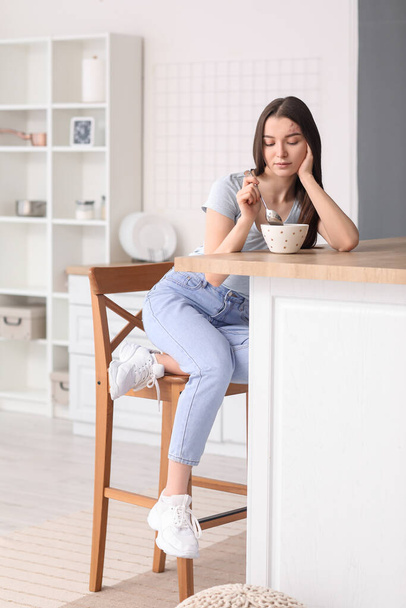 Young woman having breakfast at table in kitchen - Foto, Bild