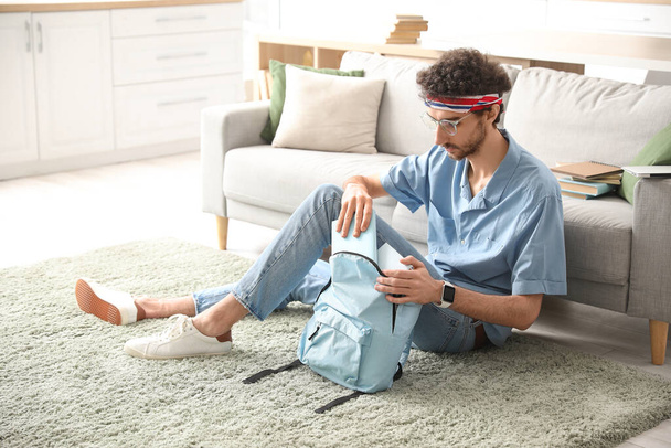 Estudiante masculino tomando libro de la mochila en casa - Foto, imagen