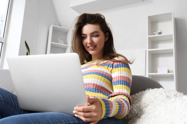 Female freelancer working with laptop on sofa at home - Photo, Image