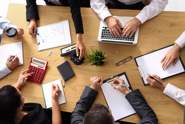 Groep van zakenmensen werkzaam aan tafel in conferentiezaal, top view - Foto, afbeelding