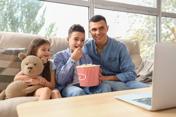 Kis gyerekek popcornnal, és az apjuk otthon néz filmet. - Fotó, kép