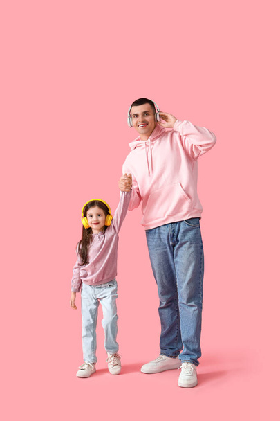 Kleines Mädchen mit ihrem Vater in Kopfhörern auf rosa Hintergrund - Foto, Bild