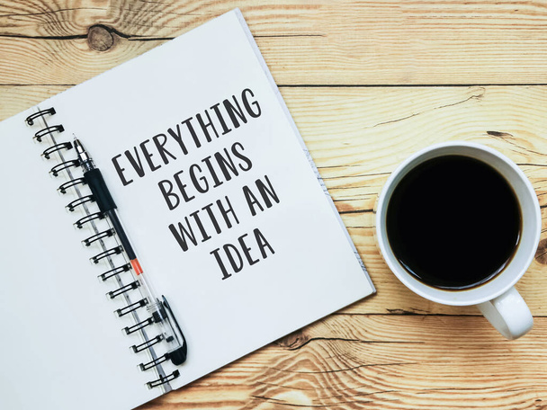 Caderno aberto com texto "Tudo começa com uma ideia" e uma xícara de café no fundo de madeira. - Foto, Imagem