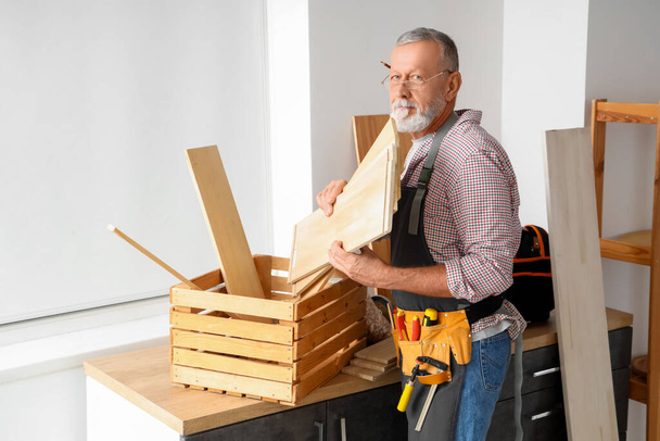 Charpentier mature avec planches en bois dans l'atelier - Photo, image