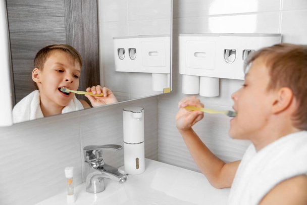 Εφηβική αυτοφροντίδα: μια αναζωογονητική στιγμή στο μπάνιο, το αγόρι βουρτσίζει τα δόντια του - Φωτογραφία, εικόνα