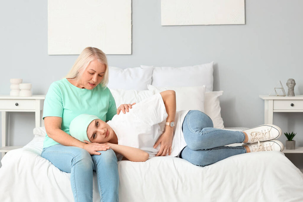 Junge Frau nach Chemotherapie mit ihrer Mutter im Schlafzimmer. Magenkrebs-Konzept - Foto, Bild