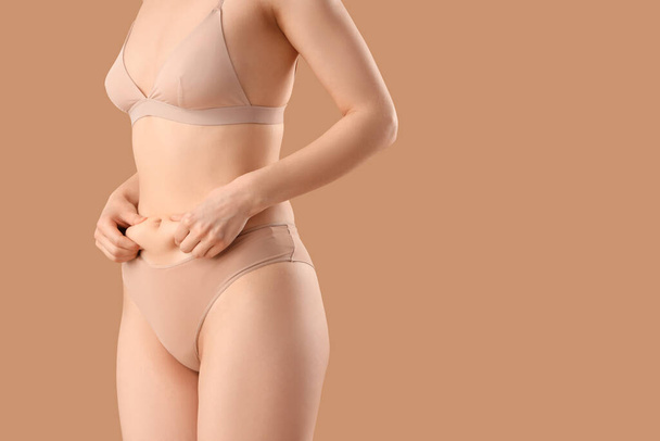 Beautiful young woman in underwear belly with cellulite problem on beige background - Fotó, kép