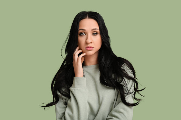 Schöne junge Frau mit dunklem welligem Haar auf grünem Hintergrund - Foto, Bild