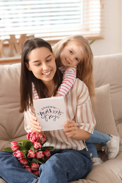 Menina parabenizando sua mãe com buquê de flores e cartão de saudação em casa. Celebração do Dia das Mães - Foto, Imagem