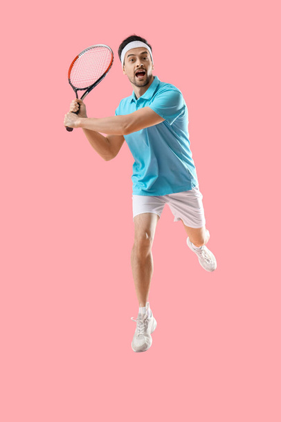 Retrato de jugador de tenis masculino saltando sobre fondo rosa - Foto, Imagen