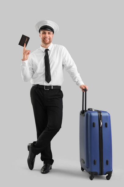 Мужской пилот с паспортом и чемоданом на светлом фоне - Фото, изображение