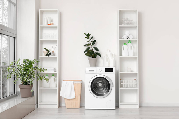 Moderni pesukone, jossa on kori ja hyllyt lähellä valkoista seinää. Kodin pesutupa - Valokuva, kuva