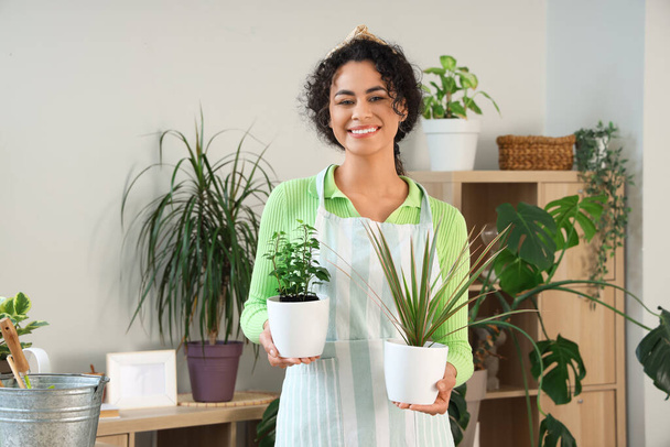 Jardinero afroamericano femenino con plantas en casa - Foto, Imagen
