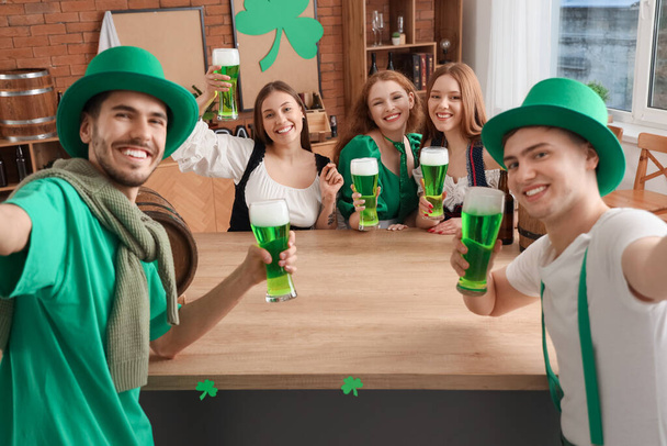 Groupe de jeunes amis avec de la bière prendre selfie dans un pub le jour de la Saint-Patrick - Photo, image