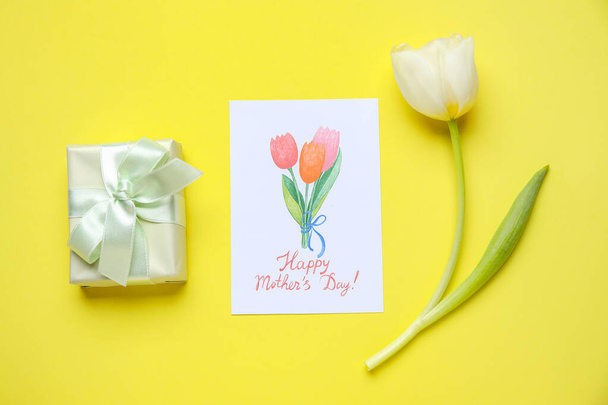Festive postcard with tulip and gift box on yellow background. Mother's Day celebration - Photo, Image