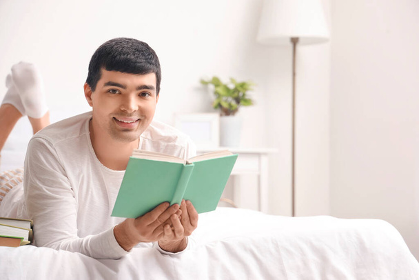 Fiatal férfi könyvet olvas a hálószobában - Fotó, kép