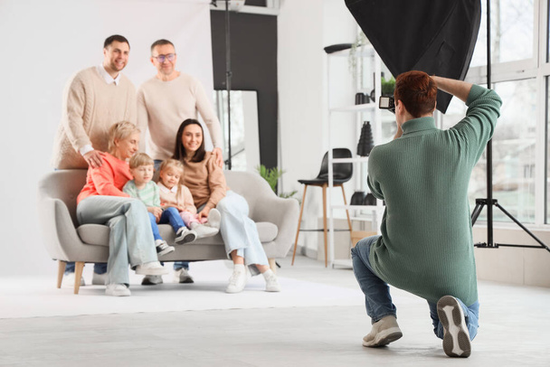 Muž fotograf fotografování velké rodiny ve studiu, pohled zezadu - Fotografie, Obrázek