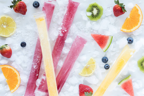 Congelaciones caseras de zumo de frutas rodeadas de hielo y trozos de fruta fresca.  - Foto, Imagen